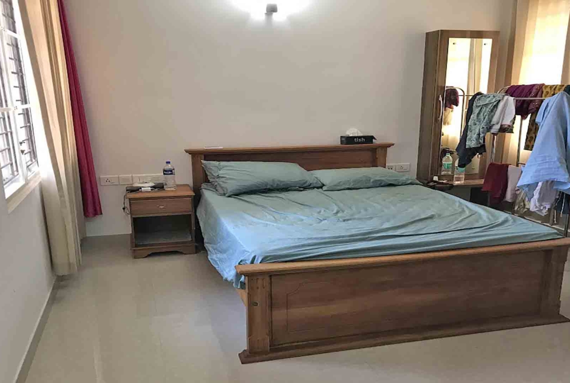 Furnished master bedroom with wooden bed and wardrobe in a 3-bedroom flat at Skyline The Edge, Thiruvalla.