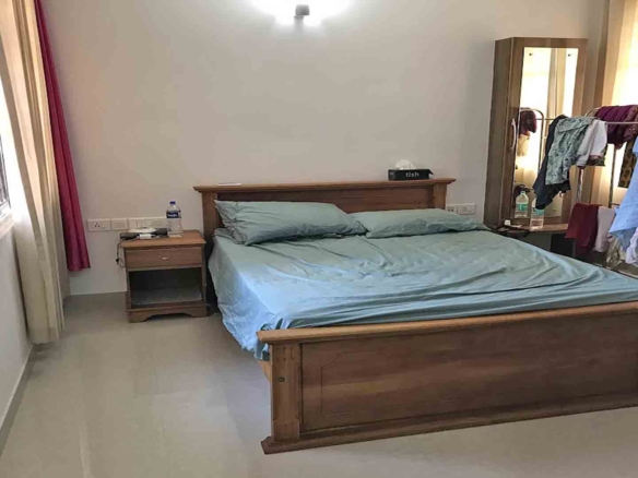 Furnished master bedroom with wooden bed and wardrobe in a 3-bedroom flat at Skyline The Edge, Thiruvalla.