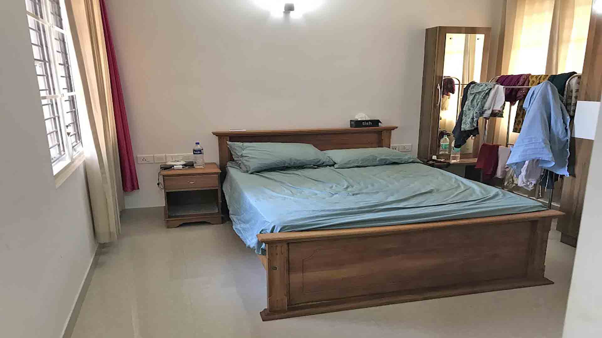 Furnished master bedroom with wooden bed and wardrobe in a 3-bedroom flat at Skyline The Edge, Thiruvalla.