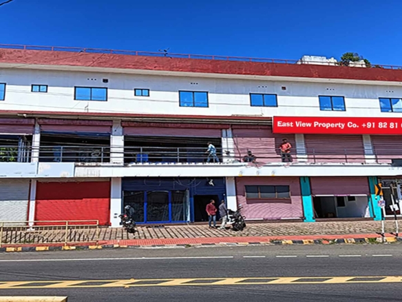 Wide-angle shot of a three-story commercial building for sale on MC Road, Chengannur, featuring multiple retail storefronts and upper-floor office spaces.