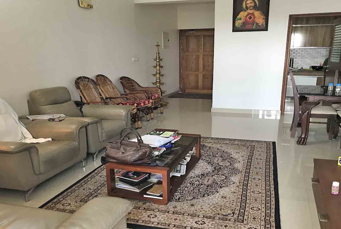 Furnished living room interior of a 3BHK flat at Skyline The Edge, Thiruvalla, featuring leather sofas and traditional decor.