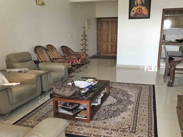 Furnished living room interior of a 3BHK flat at Skyline The Edge, Thiruvalla, featuring leather sofas and traditional decor.