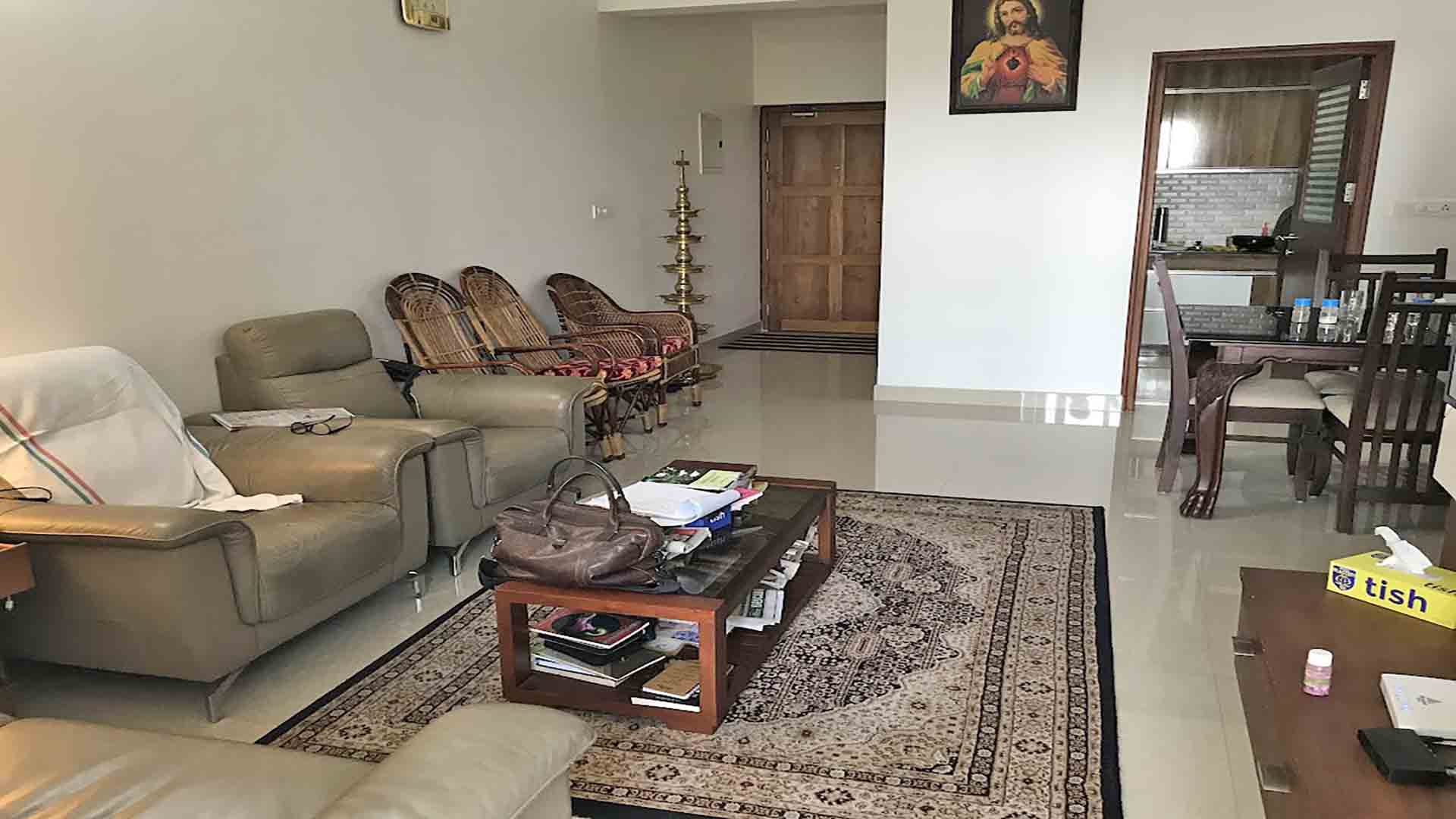 Furnished living room interior of a 3BHK flat at Skyline The Edge, Thiruvalla, featuring leather sofas and traditional decor.