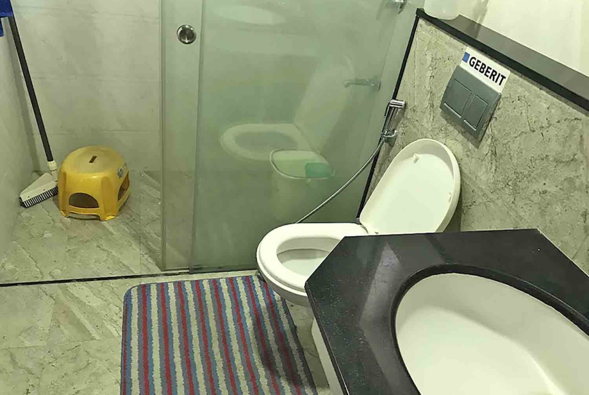 Modern bathroom interior of a 3BHK flat at Skyline The Edge, Thiruvalla, featuring a Geberit flushing system and glass shower partition.