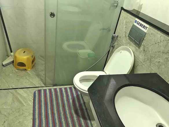 Modern bathroom interior of a 3BHK flat at Skyline The Edge, Thiruvalla, featuring a Geberit flushing system and glass shower partition.