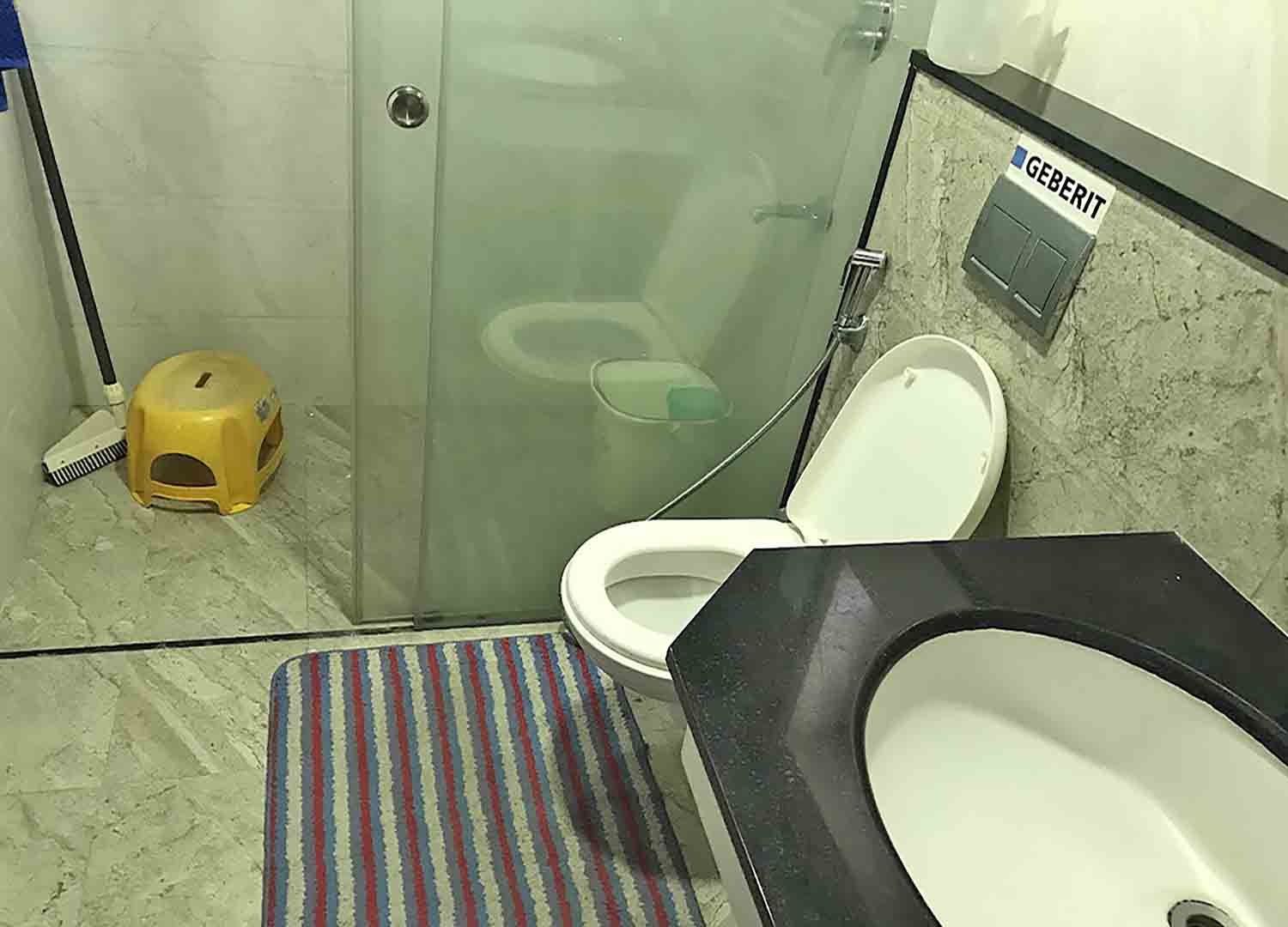 Modern bathroom interior of a 3BHK flat at Skyline The Edge, Thiruvalla, featuring a Geberit flushing system and glass shower partition.