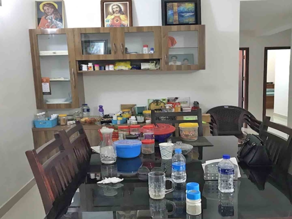 A modern dining room featuring a dark wood dining table with a glass top, matching wooden chairs, and a wall-mounted wooden crockery cabinet with glass doors.