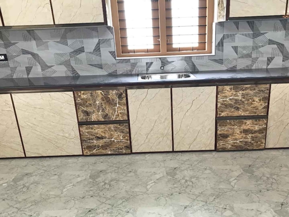 Modern modular kitchen in a 4 bedroom house for sale in Pullad, Thiruvalla, featuring marble-finish cabinets, a black granite countertop, and geometric backsplash tiles.