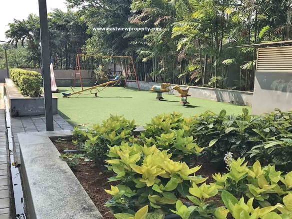 Outside view of the amenities at The Edge by Skyline, Tiruvalla, showing a children's play area with swings and a seesaw on green turf.