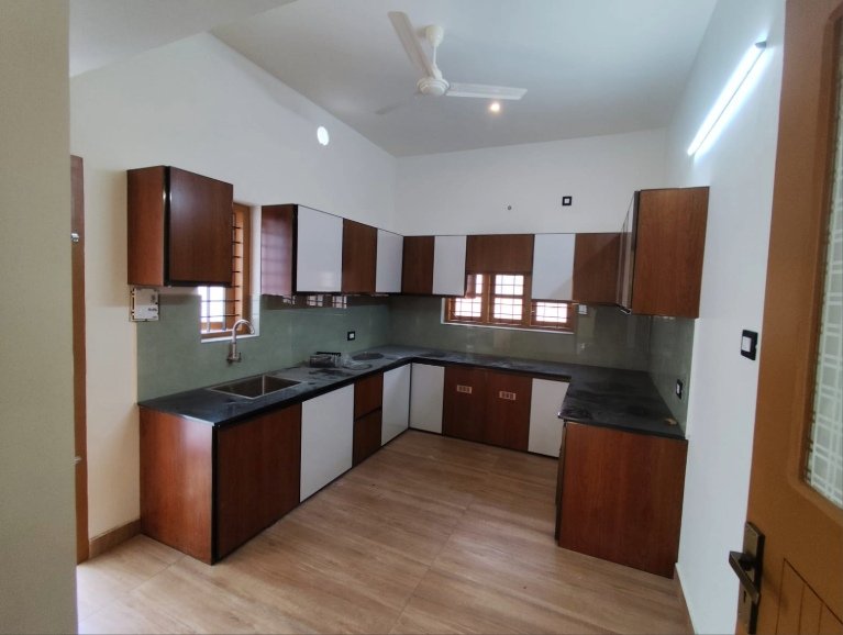 Modern modular kitchen with wooden cabinets and granite countertop in a 3 BHK villa at Eraviperoor (Eravery) , Thiruvalla.
