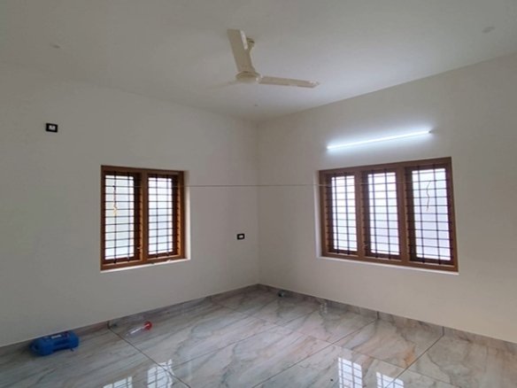 Master bedroom in a 3 BHK villa at Eraviperoor (Eravery), Thiruvalla, with tiled floors and wooden windows.