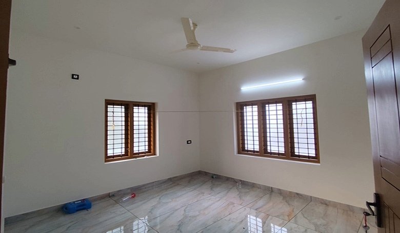 Master bedroom in a 3 BHK villa at Eraviperoor (Eravery), Thiruvalla, with tiled floors and wooden windows.