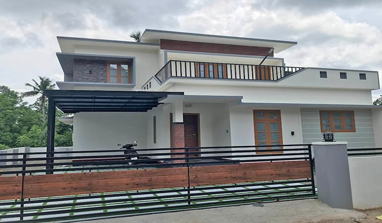Modern 2-story 3-bedroom house for sale in Eraviperoor, Thiruvalla, Kerala. Features white exterior, gated yard, and upper terrace.