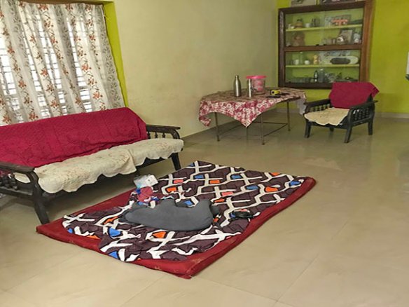 Spacious tiled living room hall with chairs, table, sofa, rug, and showcase in a 2 BHK single-storey house in Kareelamukk, Thiruvalla