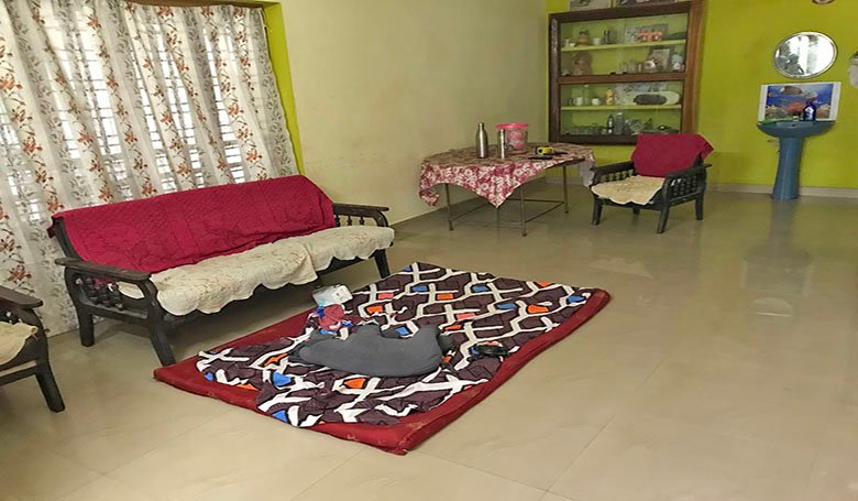 Spacious tiled living room hall with chairs, table, sofa, rug, and showcase in a 2 BHK single-storey house in Kareelamukk, Thiruvalla