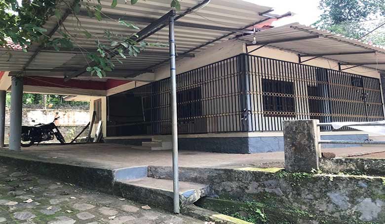 Exterior view of a 2 BHK house with metal roofing sheet extended porch and grill structure in Thiruvalla