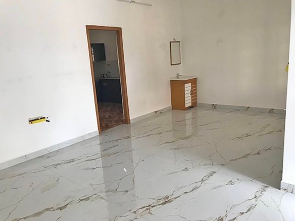 Spacious villa living room with glossy marble-look floor tiles, kitchen doorway, and washbasin vanity.