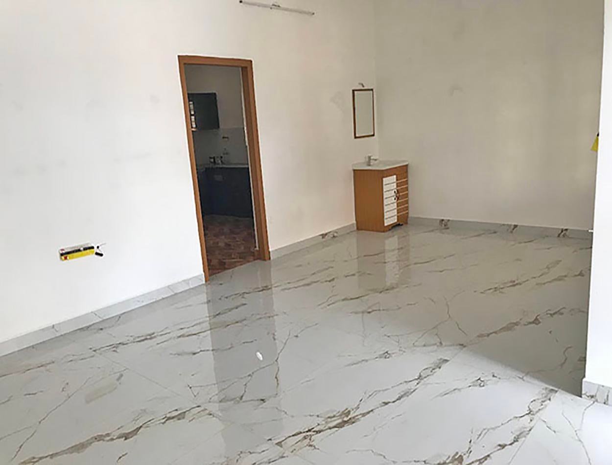 living-area-01 Spacious villa living room with glossy marble-look floor tiles, kitchen doorway, and washbasin vanity.