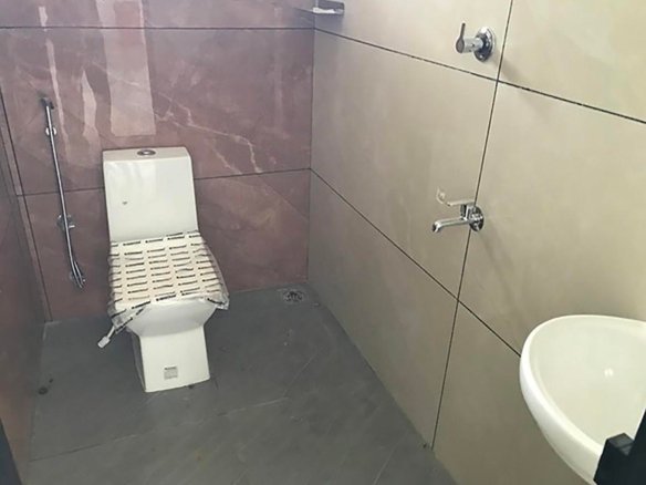 Modern bathroom with floor-mounted water closet, health faucet, chrome fixtures, ceramic washbasin, and tiled walls.