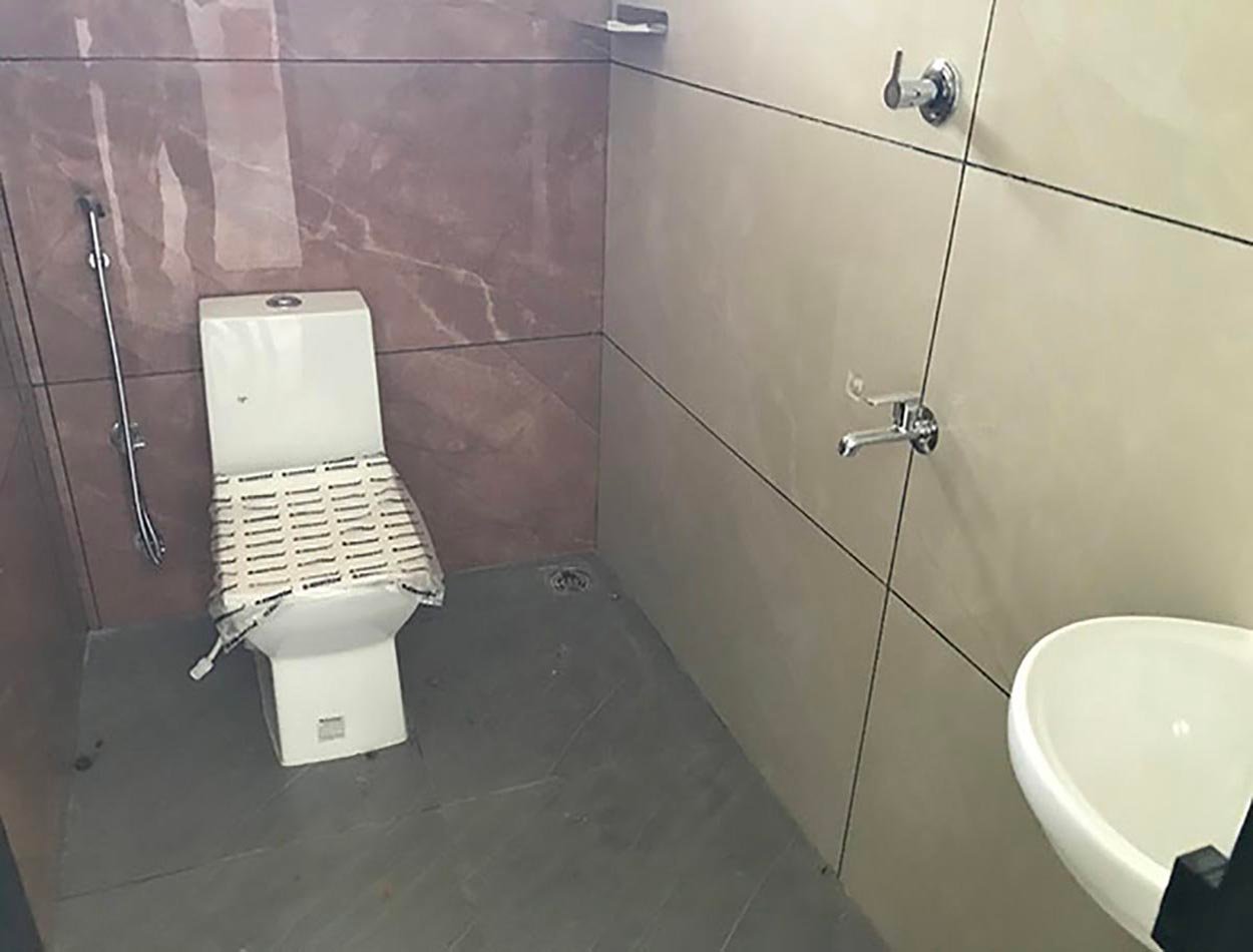 sample-toilet-bath Modern bathroom with floor-mounted water closet, health faucet, chrome fixtures, ceramic washbasin, and tiled walls.